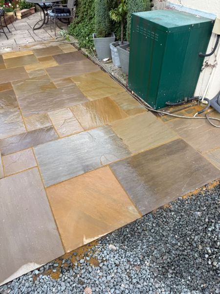 Slab path running past a green outdoor cabinet towards the seating area