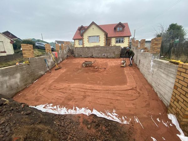 The screeded sand bed between the new walls, with the compactor in use