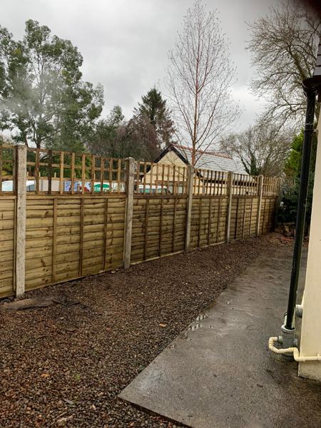 Overlap panels with trellis tops on concrete posts beside a bark border and path