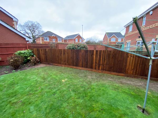 Finished brown close-board fence enclosing the lawn