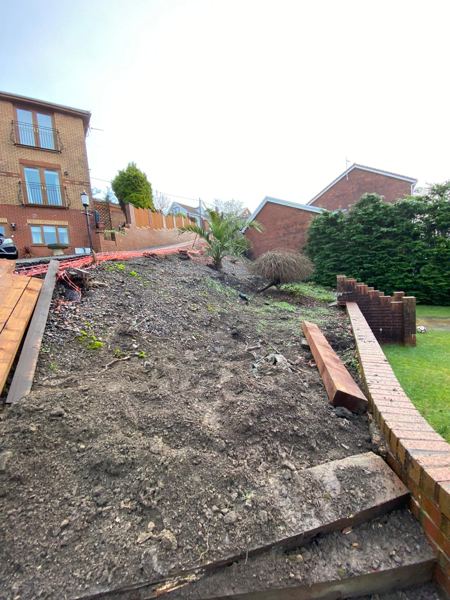 Before: a bare, steep bank of soil above old brick walls