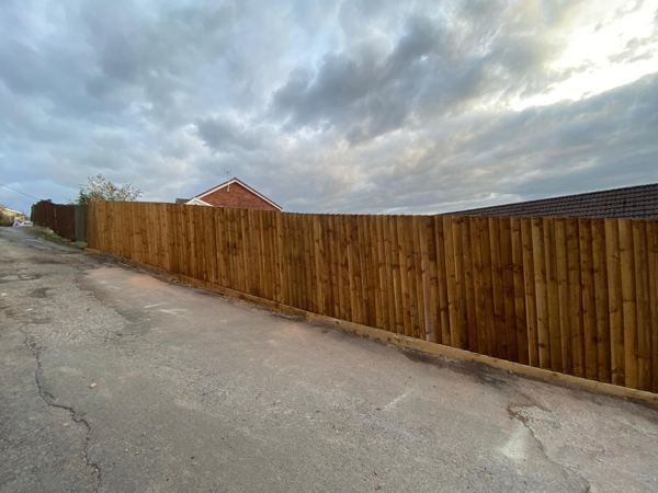 Long run of featheredge fence with a gravel board beside the lane