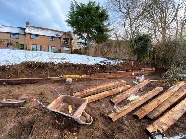 Heavy treated timbers laid out beside a string line on the dug bank