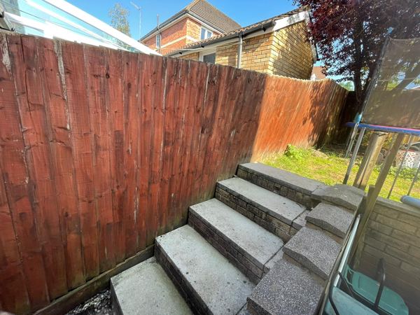 An old stained close-board fence beside concrete garden steps