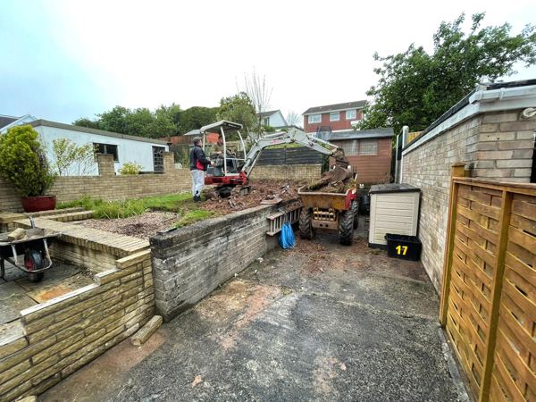 A mini digger and dumper stripping out an old raised lawn
