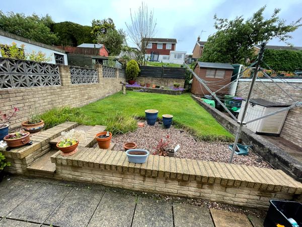 Before: a sloping lawn, gravel and pots behind a low buff brick wall
