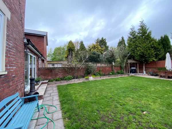 The same side of the garden with a red-brick wall and trellis along the boundary