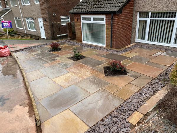 The finished sandstone front patio with three planting pockets and slate borders