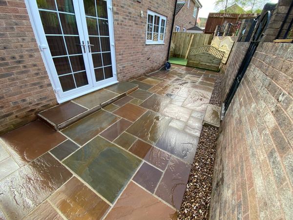 Rust, plum and green sandstone outside the French doors, with a gravel margin