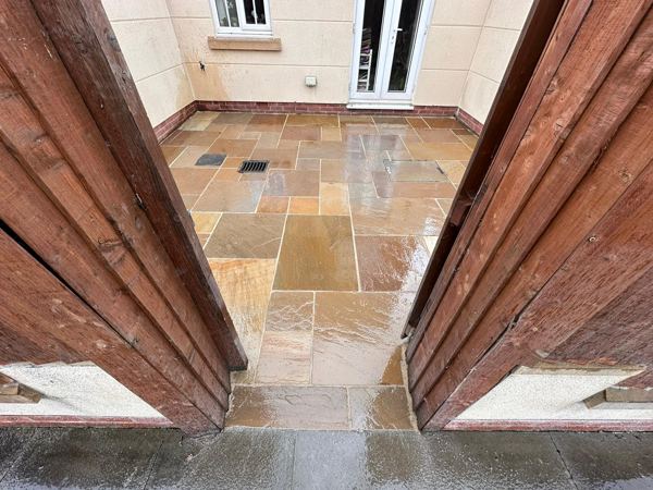 The sandstone courtyard, wet after rain, seen through the open timber gates