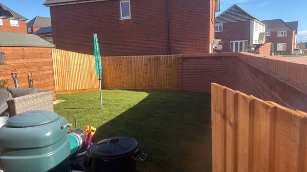 The finished garden with new close-board fencing, a brick wall and a freshly turfed lawn