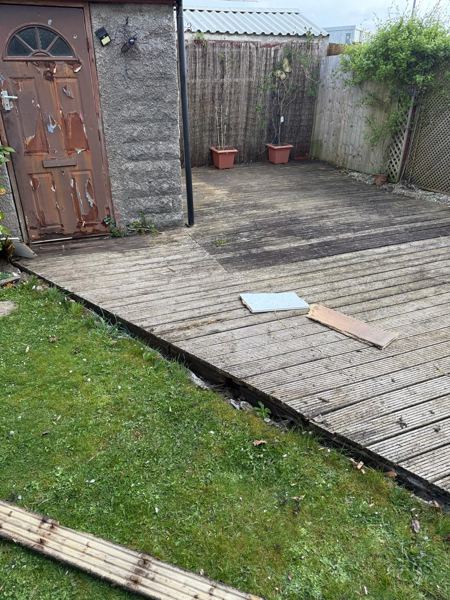 Before: the weathered deck running up to the outbuilding door, with a loose slab lying on it