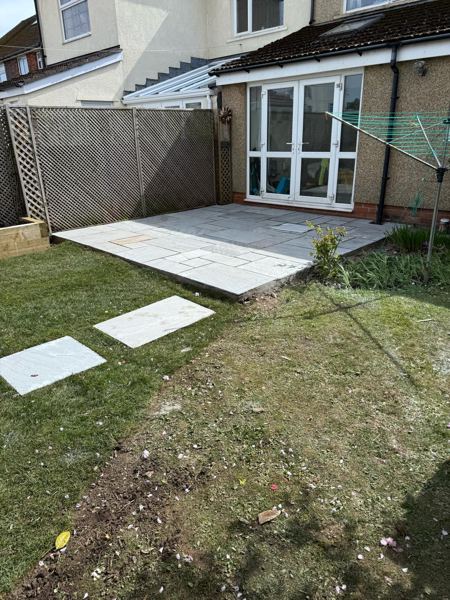 The finished grey slab patio outside the French doors, with stepping stones across the lawn