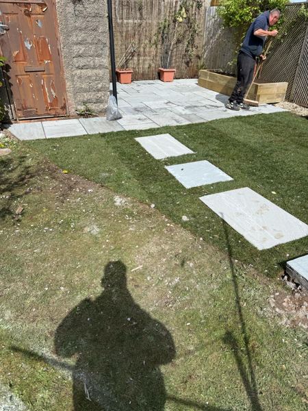 Brushing down the new paving by the outbuilding, with the stepping stones set into the grass