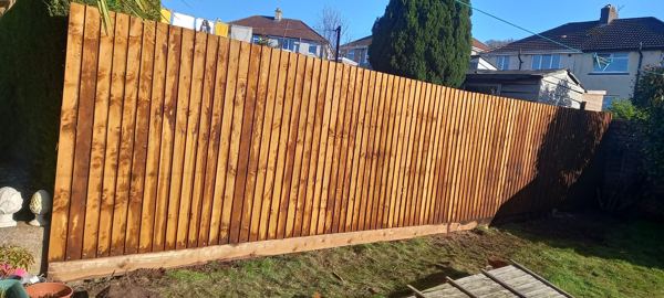 Finished featheredge fence with a timber gravel board, running down the sloping garden