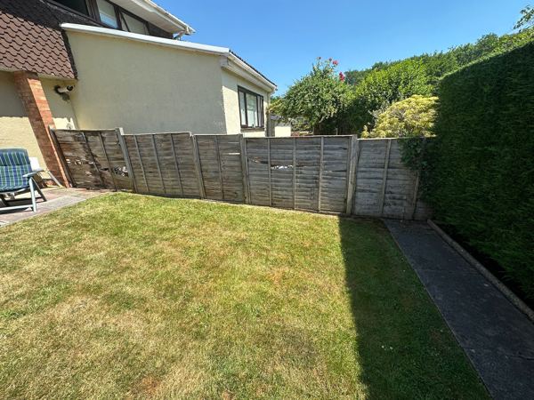 Before: low, weathered lap panels along the end of the lawn