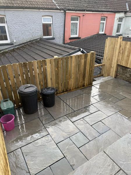 The lowest paved level by the house, with room for the bins behind a timber fence