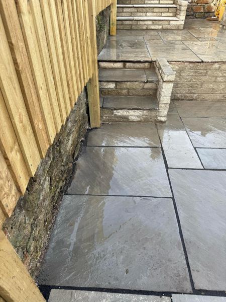 Rain-washed grey slabs at the foot of the steps, beside the old stone wall