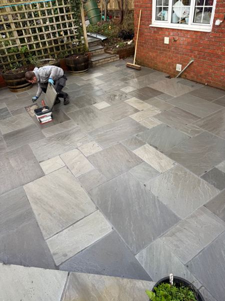 Joints being filled by hand across the lower patio