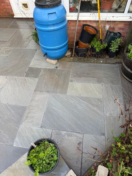 Grey slabs by the house, with the water butt on its own raised slab