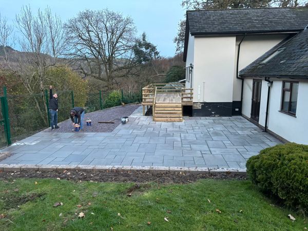 The new grey sandstone patio at dusk, with the refinished balcony and steps