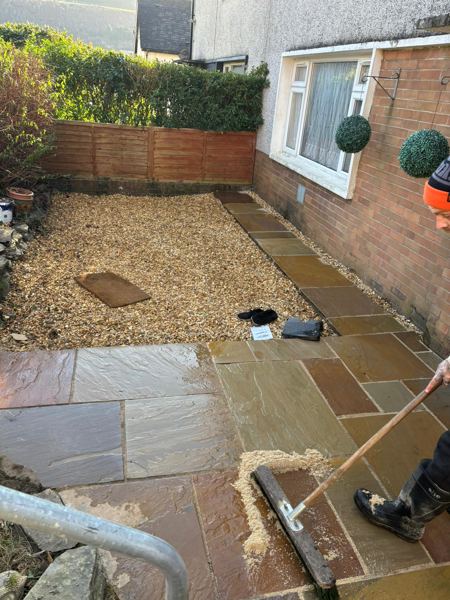 Brushing sand into the joints of the new path beside the bay window