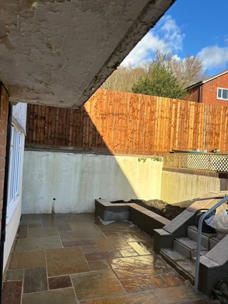 Sandstone paving under the overhang, with steps and a handrail on the right
