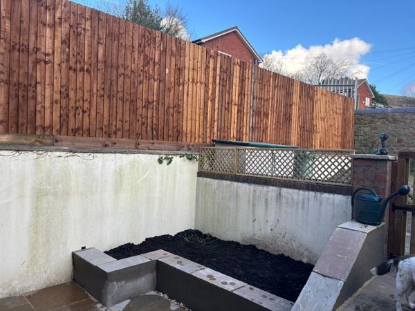 The raised bed filled with soil beside sandstone-capped steps