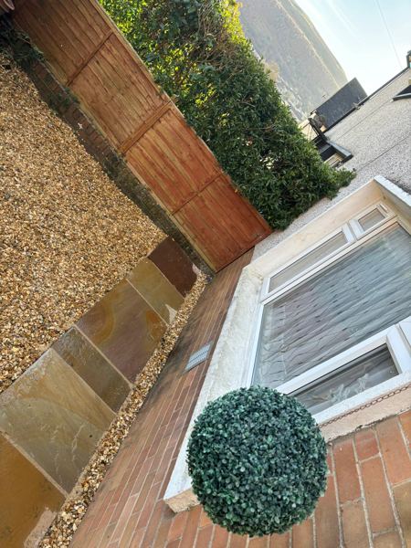 Sandstone slabs edged with gravel beside the house, with the hillside beyond