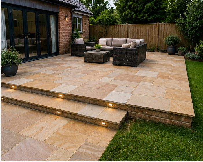 Indian sandstone patio with lit steps down to the lawn